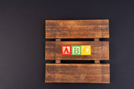 Letter wooden cube on black background with educational conceptの写真素材