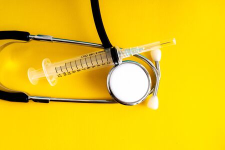 Stethoscope and syringe with yellow background.の写真素材