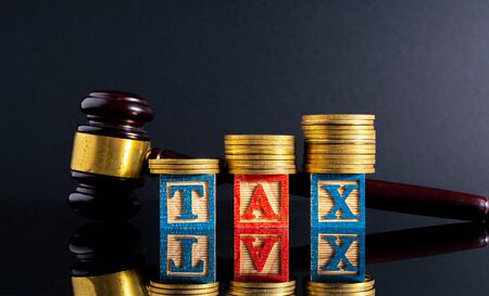 Gavel hammer and stacking coins and tax letter cube with low light view.の写真素材