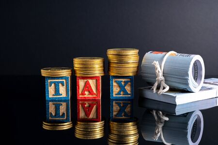 Coins stacking and tax letter cube with low light view.の写真素材