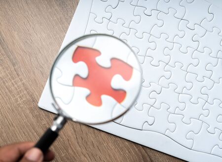 Magnifier glass and jigsaw puzzle background with education concept. Focused on puzzle.の写真素材