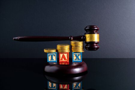 Gavel hammer and stacking coins and tax letter cube with low light view.の写真素材