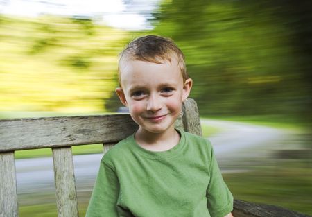 Young boy spinning on a bench.  Blurred background with lots of copy space.の写真素材