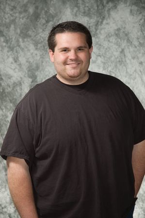 overweight young man posing in front of portrait backdropの写真素材