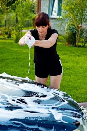 Adult cleaning her car outsideの写真素材