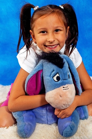Short girl with the soft toy on the blue mosaic background の写真素材