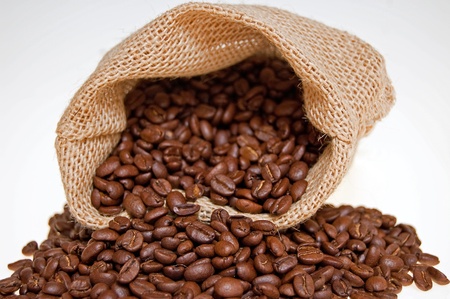 grains of the coffee spilling out from the sack on the white backgroundの写真素材