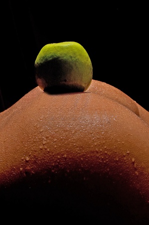Green apple on the bare ass women in the sensual act in the twilight of lightの写真素材