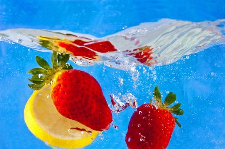 Fresh fruits falling into the water on a blue mosaic backgroundの写真素材