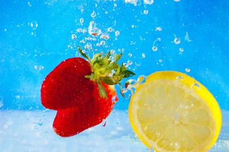 Fresh fruits falling into the water on a blue mosaic backgroundの写真素材