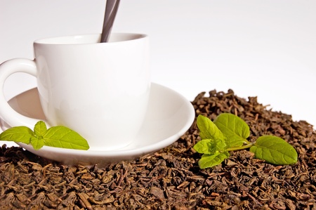 Green tea leaves and a cup of brewed tea with mint leavesの写真素材