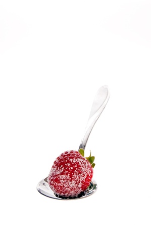 Fresh strawberries dipped in sugar on a spoonの写真素材