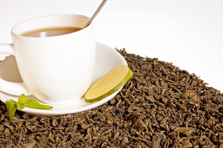 Green tea leaves and a cup of brewed tea with mint leavesの写真素材