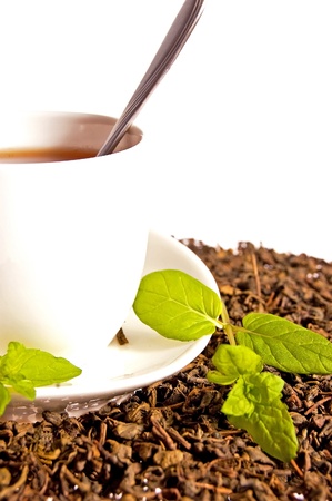 Green tea leaves and a cup of brewed tea with mint leavesの写真素材