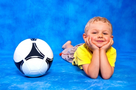Boy and the ball lying on a blue mosaic backgroundの写真素材