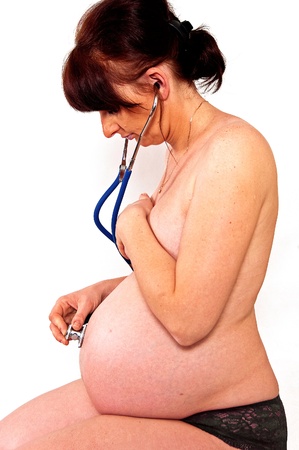 Pregnant woman listening through a stethoscope beating hearts of their babyの写真素材