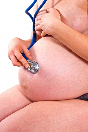 Pregnant woman listening through a stethoscope beating hearts of their babyの写真素材