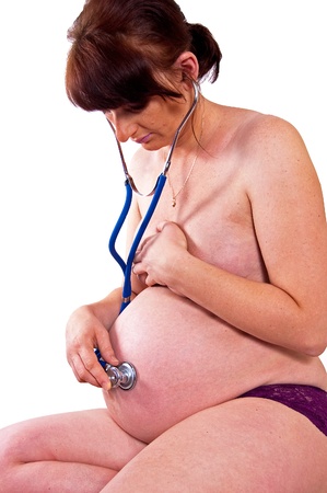 Pregnant woman listening through a stethoscope beating hearts of their babyの写真素材