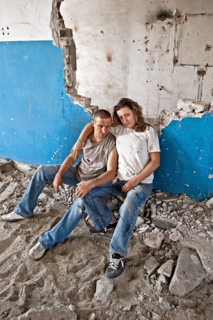 Homeless young couple sitting in the ruins of an old houseの写真素材