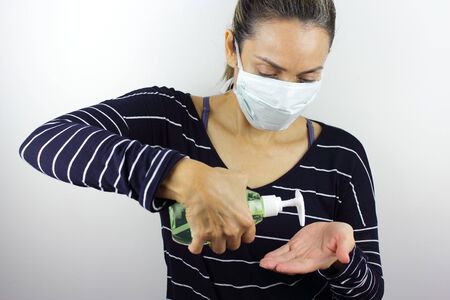 Latin American woman wearing a virus mask with a bottle of hand sanitizerの写真素材
