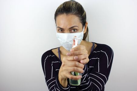 Latin American woman wearing a virus mask with a bottle of hand sanitizerの写真素材