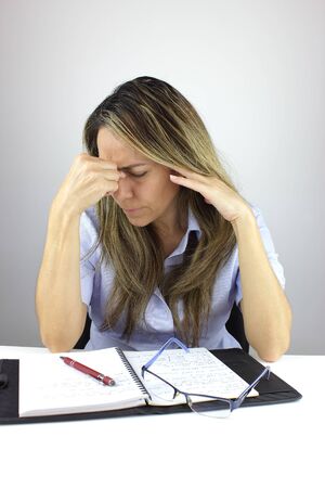Beautiful business woman working from home with a migraineの写真素材