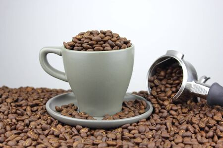 Coffee beans in a cup and saucer with a group handleの写真素材