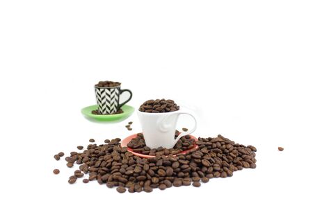 Dark roasted coffee beans in a cup and saucerの写真素材