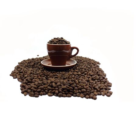 Dark roasted coffee beans in a cup and saucerの写真素材