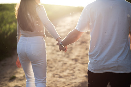 Couple in love holding hands, walking down the road into the sun.の写真素材