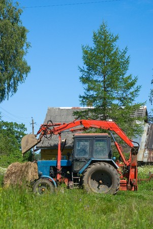 Tractor with a ladle before the farmer house