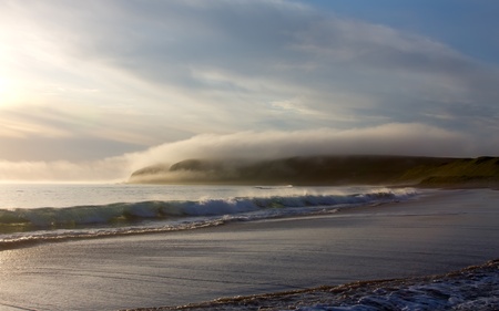 Solar ocean coast, beach, fog slipping from mountainsの写真素材