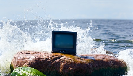 unusual photo of TV in ocean on stoneの写真素材