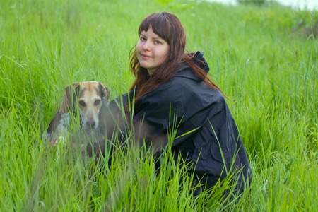 girl dressiruem dog outdoor. hound in grass fields with hostessの写真素材