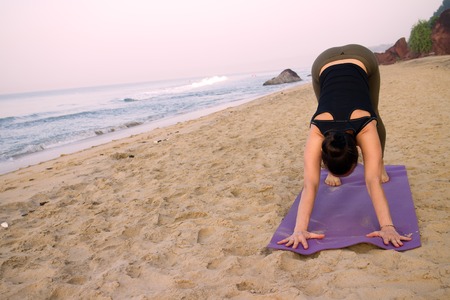 outdoor on beach girls yoga trainer at home yoga. ahead of the ocean around exotic Indiaの写真素材
