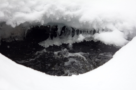 Snowing over frozen river, snow bridgesの写真素材