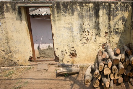 Indian village. Firewood stacked in pile in front of house and fence (construction waste and trunks cutting of fruit trees ), house of poorの写真素材