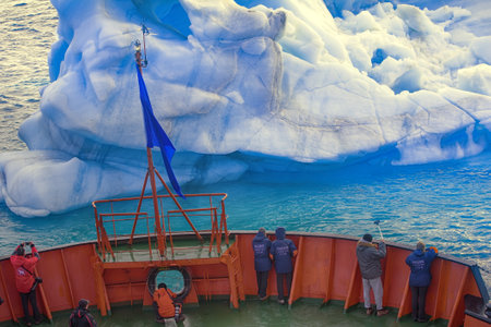 Franz-Joseph Land - 10 July 2016: Tourist cruise in high Arctic. Ship sails close to small iceberg. But we should remember that 90% of ice mountain is under water. Titanic Iceberg was a little moreのeditorial素材