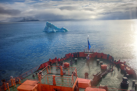 Franz-Joseph Land - 10 July 2016: Tourist cruise in high Arctic. Ship sails close to small iceberg. But we should remember that 90% of ice mountain is under water. Titanic Iceberg was a little moreのeditorial素材