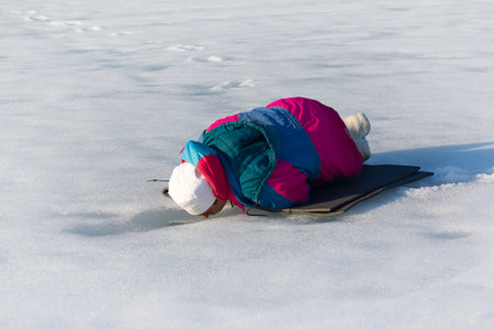Russia, Nickel - April 30, 2016: Original Northern fishing. Lapp-woman catches fish under ice...