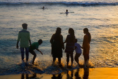 VARKALA, INDIA - Jan 2, 2016: Indians with their families on beach at sunset, swimmingのeditorial素材