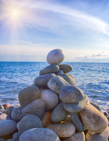 Entertainment for beachgoers. Cairn, cone is formed of pebbles on seashore, with waves alwaysの写真素材