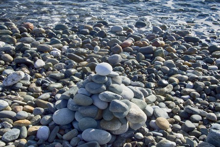 Entertainment for beachgoers. Cairn, cone is formed of pebbles on seashore, with waves alwaysの写真素材