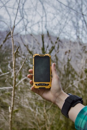smartphone is ip68 protected in forest background. girl journey in woodlandの写真素材