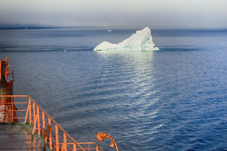 Franz-Joseph Land - 10 July 2016: Tourist cruise in high Arctic. Ship sails close to small iceberg. But we should remember that 90% of ice mountain is under water. Titanic Iceberg was a little moreのeditorial素材