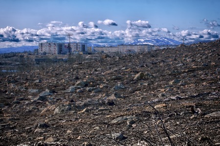 Pollution of environment. Debris, dead trees in surroundings of metallurgical plant. Factory smoke pipe, visible piles of oreの写真素材