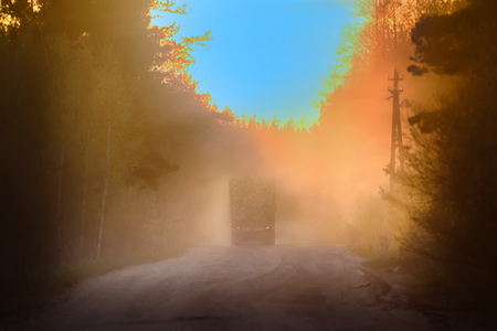 Blurred background. forestry management truck loaded with wood logs in mist at sunset on a forest roadの写真素材