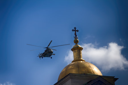 Saint Petersburg, Russia - May 9, 2017: Mi-8amtsh Terminator, NATO code Hip. Russuan Transport-attack helicopters flies over city over temple with Golden church dome with cross. Concept of pacifismのeditorial素材