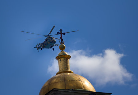 Saint Petersburg, Russia - May 9, 2017: Mi-8amtsh Terminator, NATO code Hip. Russuan Transport-attack helicopters flies over city over temple with Golden church dome with cross. Concept of pacifismのeditorial素材