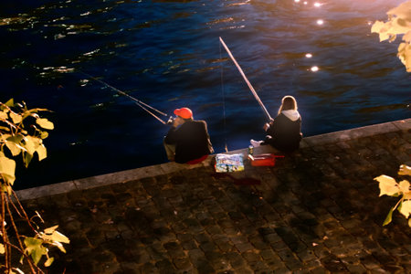 Paris, France - September 22, 2017: Night fishing on river Seine. Two fishermen with float rods, top viewのeditorial素材